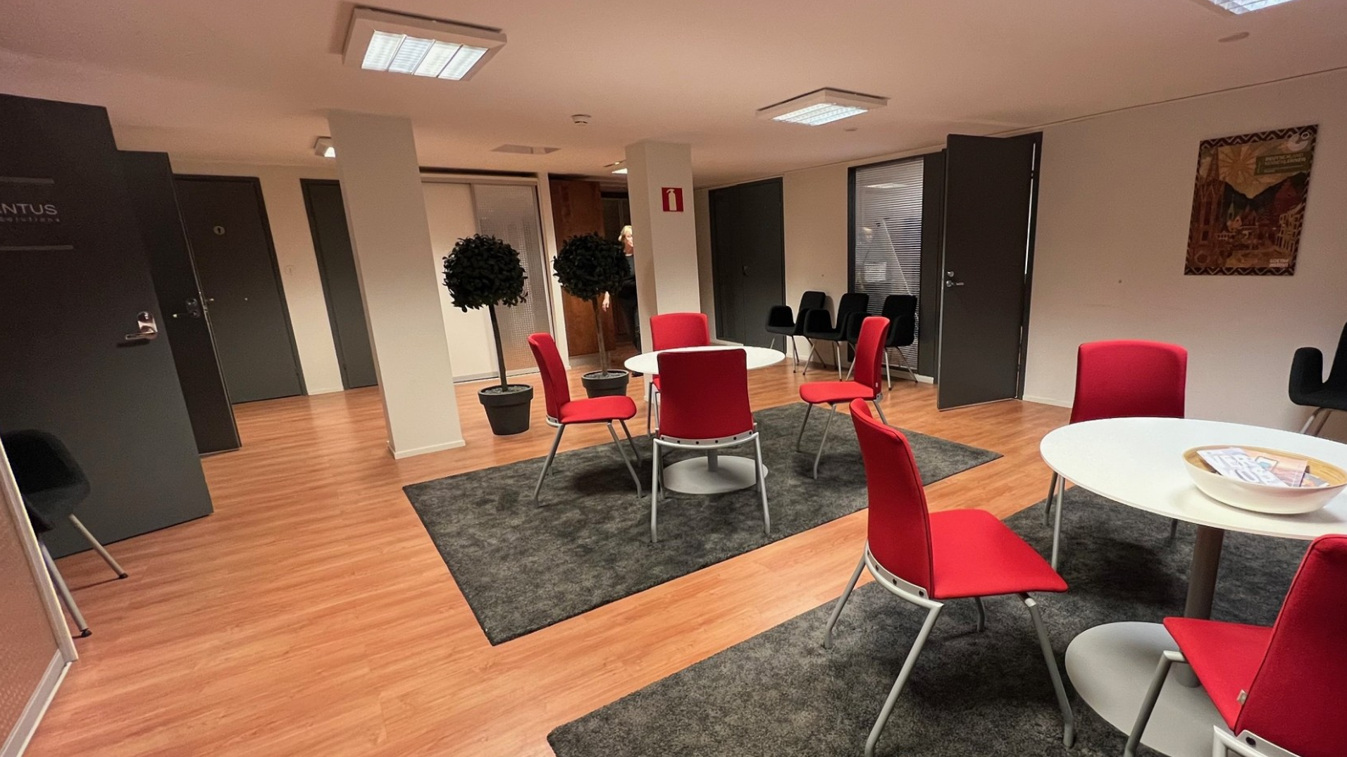 A lounge at the Mercantus offices with red chairs and round tables.